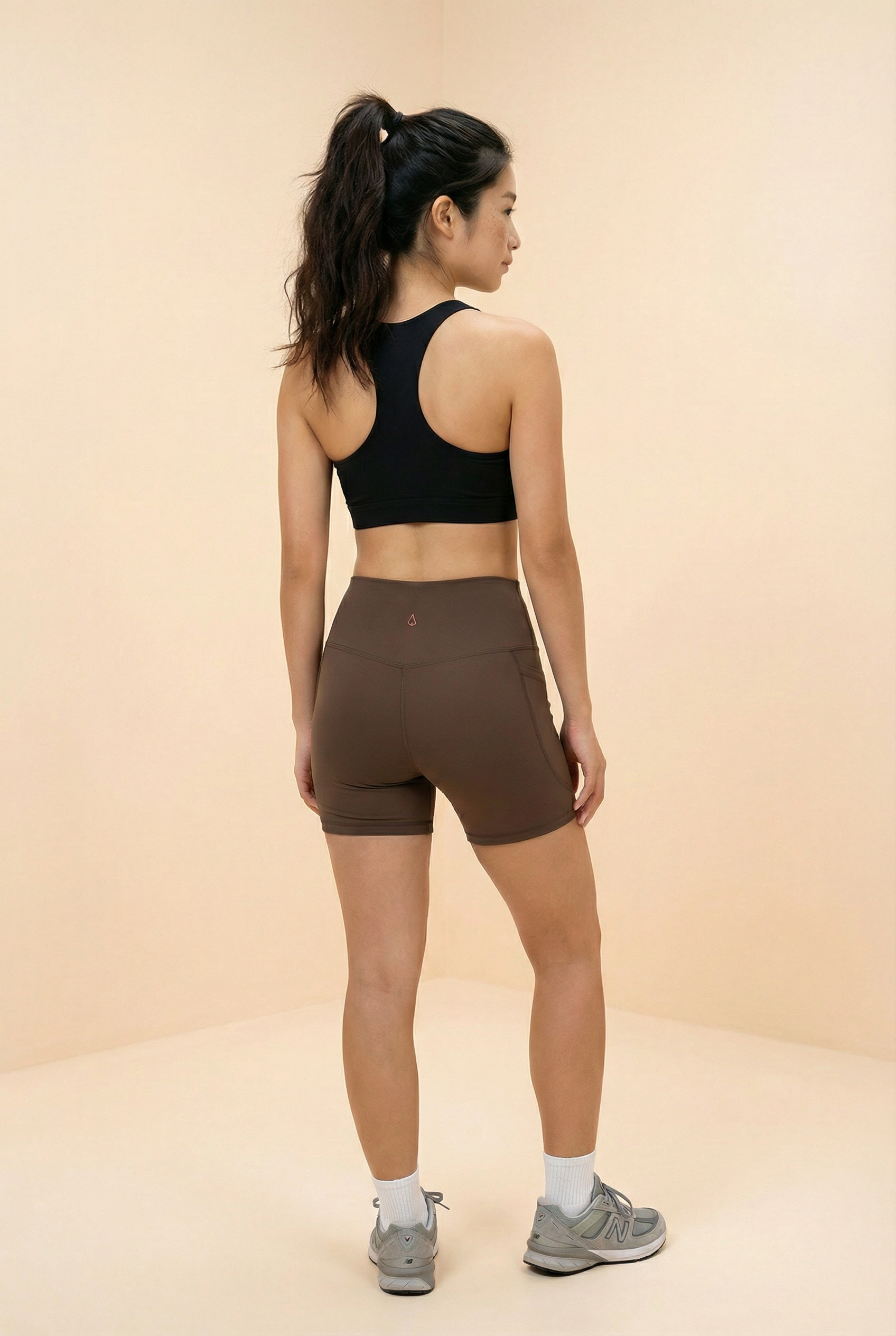 Women wearing black sports bra and brown biker shorts with pockets