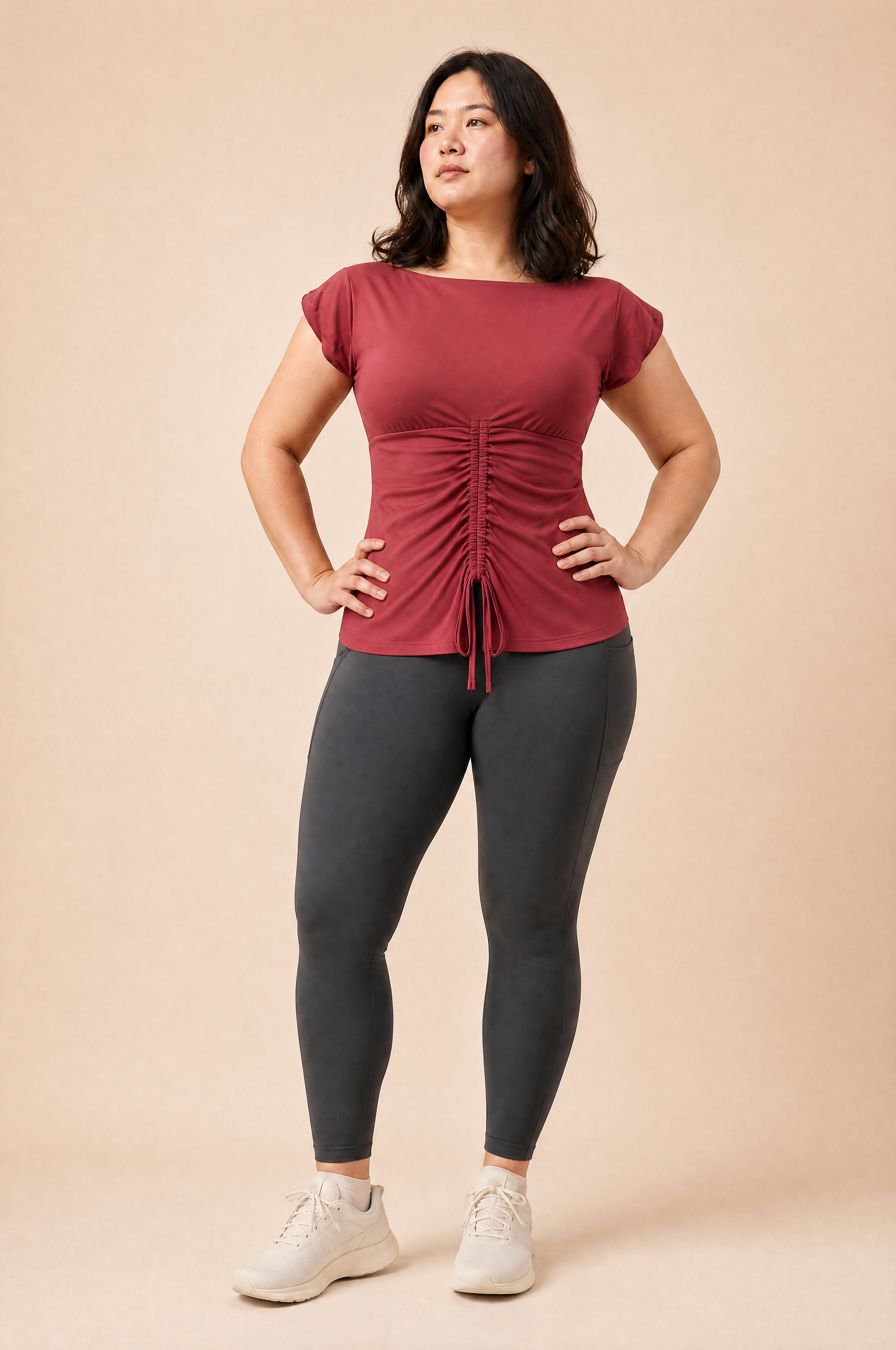Woman wearing a red top and black leggings on a beige background